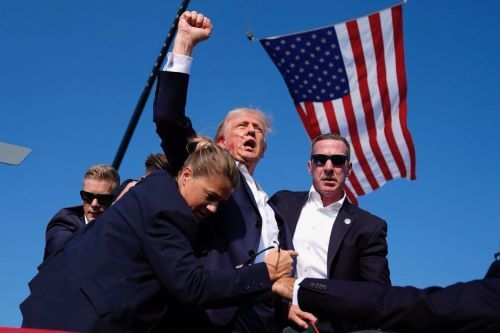 ژست ترامپ بعد از زنده ماندن در ترور نافرجام زیر پرچم آمریکا در حلقه نیروهای امنیتی (عکس)